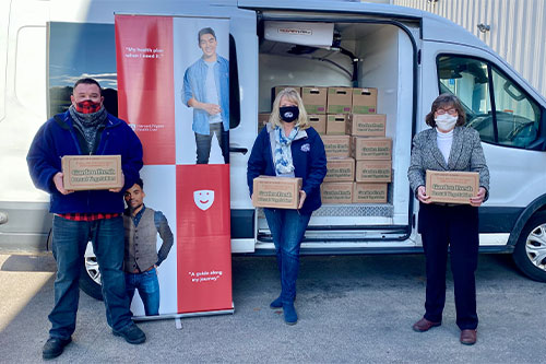 three people holding meals for meals of thanks campaign