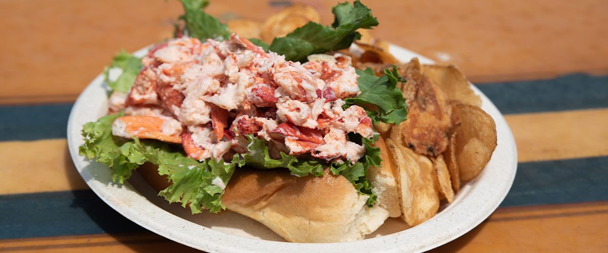 lobster roll on a plate with chips